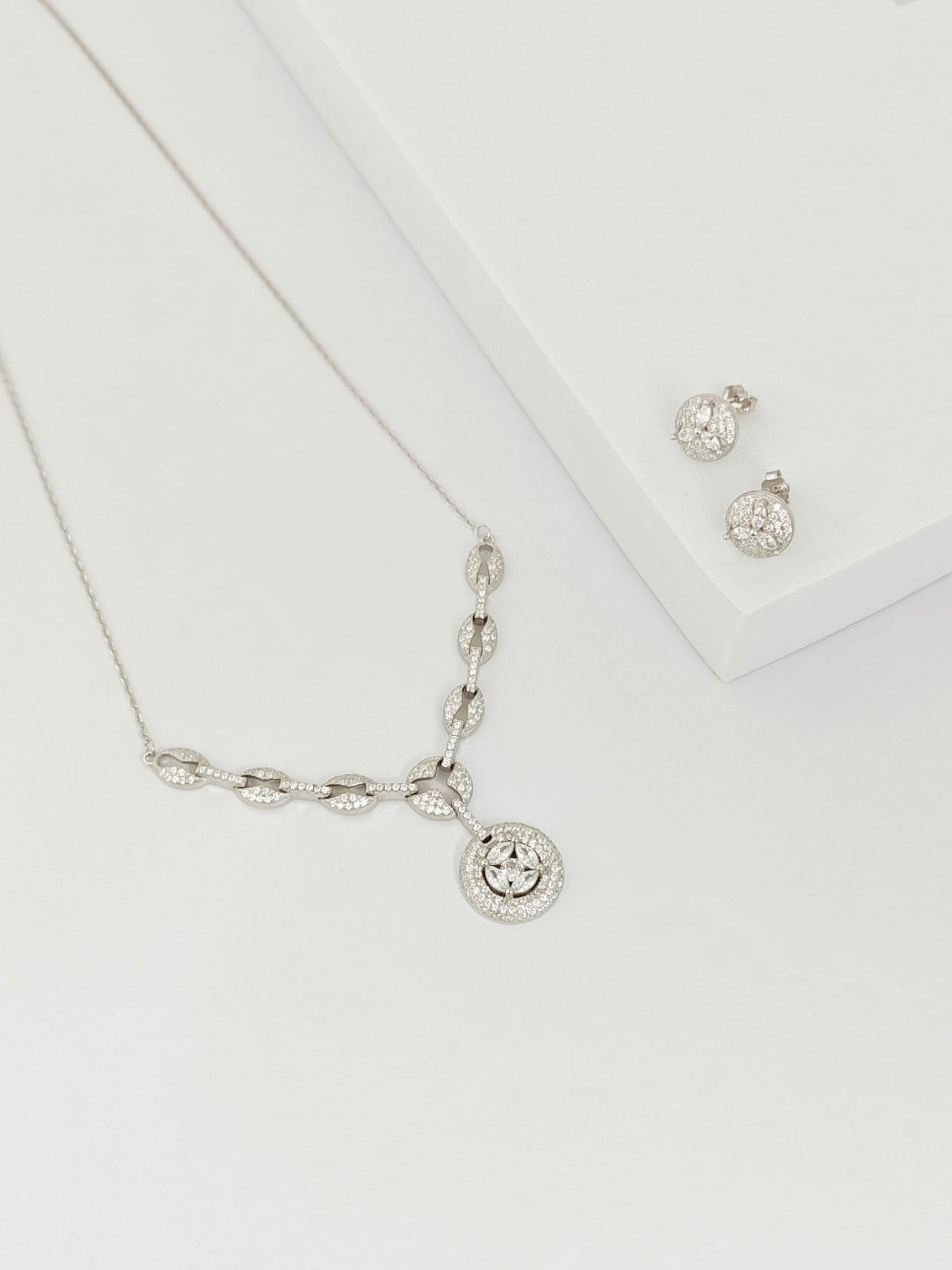 Silver necklace and earrings on a white background
